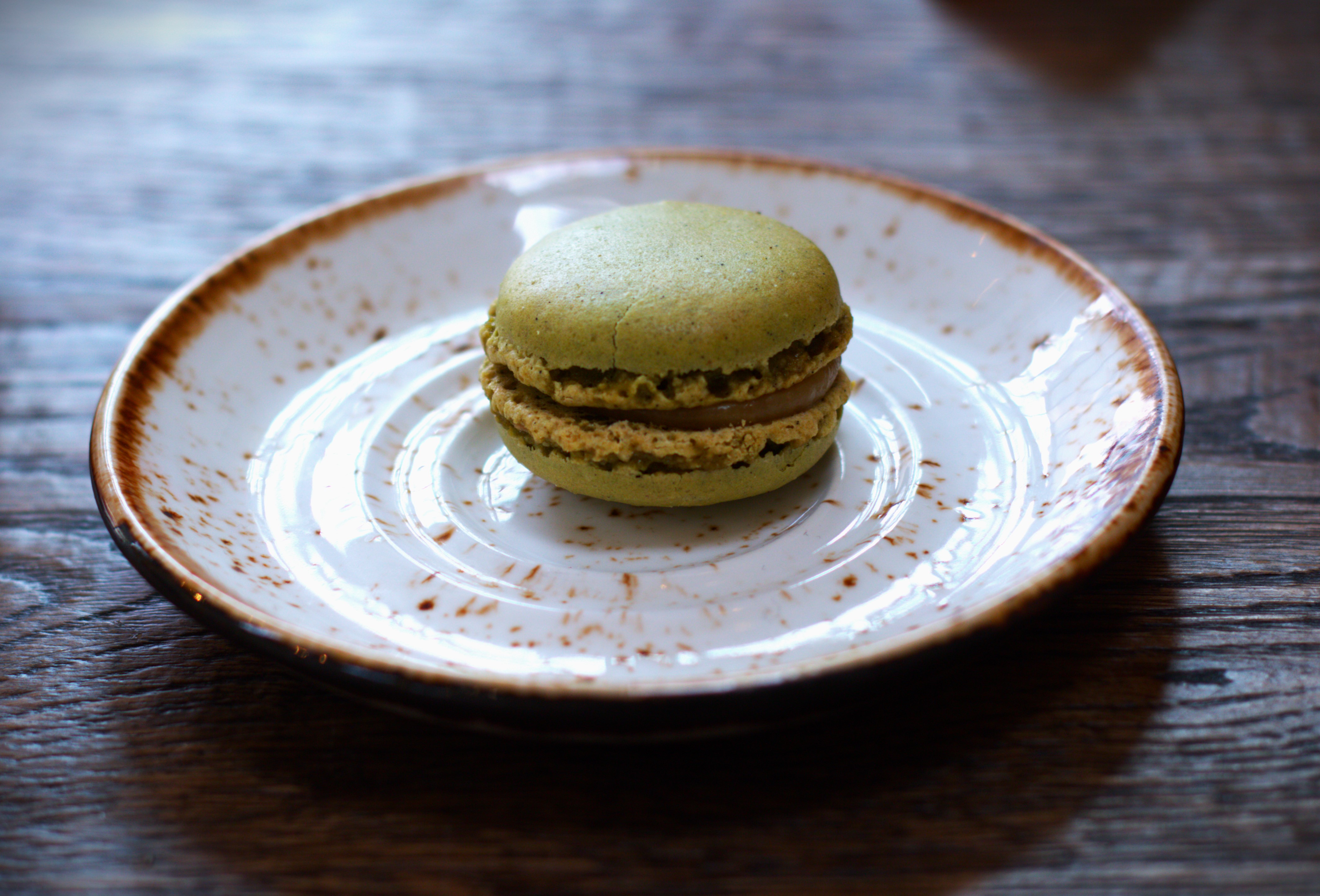 Green macaroon on a speckled white plate